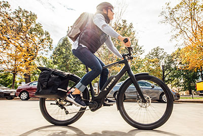 Ein Mann fährt mit einem schwarzen Fahrrad, der Marke Trek, eine Straße entlang.