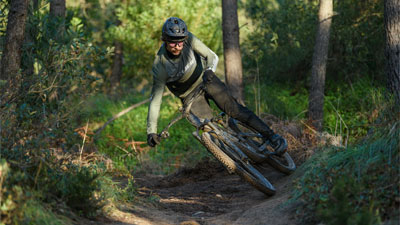 Radfahrer fährt schräg durch den Wald auf einem Cube Stereo Fully Mountainbike.